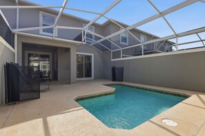 A covered outdoor swimming pool with a glass ceiling, a sliding glass door entrance, and a patio area with a table and chairs. - Spacious Champions Gate Townhome - Splash Pool - Walk to Resort - Near Disney (Kissimmee)
