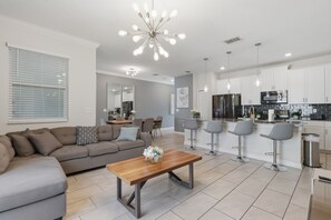 Een moderne woonkamer met een bank, een salontafel en een eethoek met stoelen.