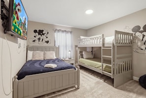Un dormitorio con una cama individual, una litera, un televisor y adornos en la pared.