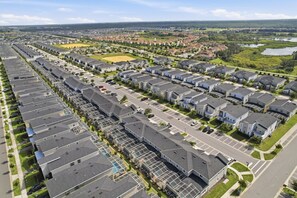 A residential area with modern houses, a central road, and surrounding greenery. - Spacious Champions Gate Townhome - Splash Pool - Walk to Resort - Near Disney (Kissimmee)