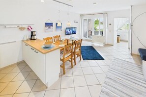 A compact kitchen with a dining area, a TV, and a view to the outside. - Holiday apartment Little Crab (Langeoog)