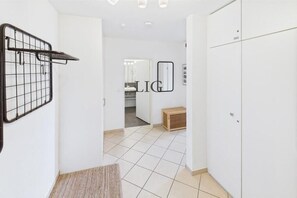 A hallway with a metal rack, a mirror, and a door leading to a room. - Holiday apartment Little Crab (Langeoog)