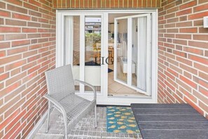 A balcony with a wicker chair, a small table, and a blue mat with fish patterns. - Holiday apartment Little Crab (Langeoog)