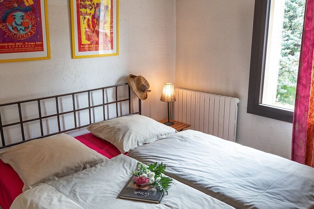 A hotel room with a bed, a lamp, and posters on the wall.