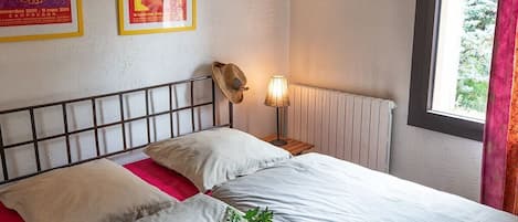 A hotel room with a bed, a lamp, and posters on the wall.