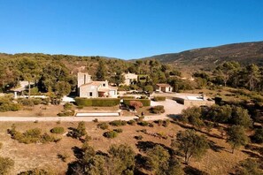 A rural property with multiple buildings, including a main house and several smaller structures, surrounded by natural vegetation and hills in the background. - Cabin in Ménerbes with swimming pool (Ménerbes)