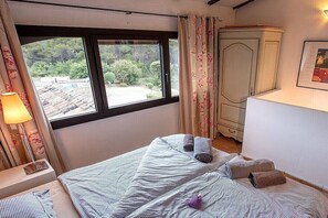 A bedroom with a bed, a window, a wardrobe, and a lamp. - Cabin in Ménerbes with swimming pool (Ménerbes)