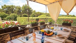 Un espace de restauration en plein air avec une table dressée pour deux personnes, entouré de murs en pierre et de plantes en pot.