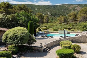 A pool area with lounge chairs, surrounded by well-maintained hedges and a stone wall. - Cabin in Ménerbes with swimming pool (Ménerbes)