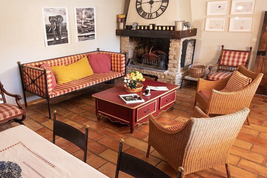 Un salon chaleureux avec une cheminée, un canapé, des fauteuils en osier et une table basse.