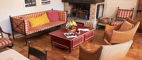 Una sala de estar acogedora con chimenea, un sofá, sillones de mimbre y una mesita de centro.