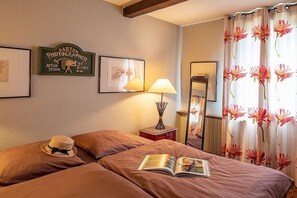 A hotel room with a bed, a lamp, a framed sign, and a mirror.