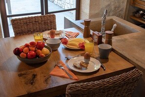 Ein Frühstückstisch mit einer Fruchtschale, einer Toastplatte, einem Orangensaftglas und einer Kaffeekanne.