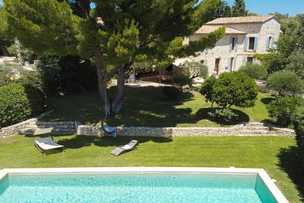 Piscina com duas espreguiçadeiras e um muro de pedra.