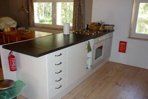 A kitchen with a central island, white cabinetry, and a window providing natural light. - Holiday home with 2 bedrooms (Vimmerby - Rumskulla)