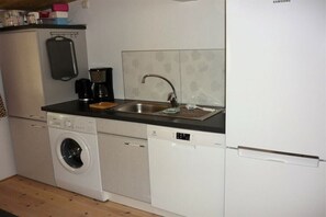 A compact kitchen with a washing machine, dishwasher, and a coffee maker. - Holiday home with 2 bedrooms (Vimmerby - Rumskulla)