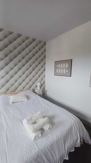 Een hotelkamer met een bed, nachtkastje, lamp en een kunstwerk aan de muur.