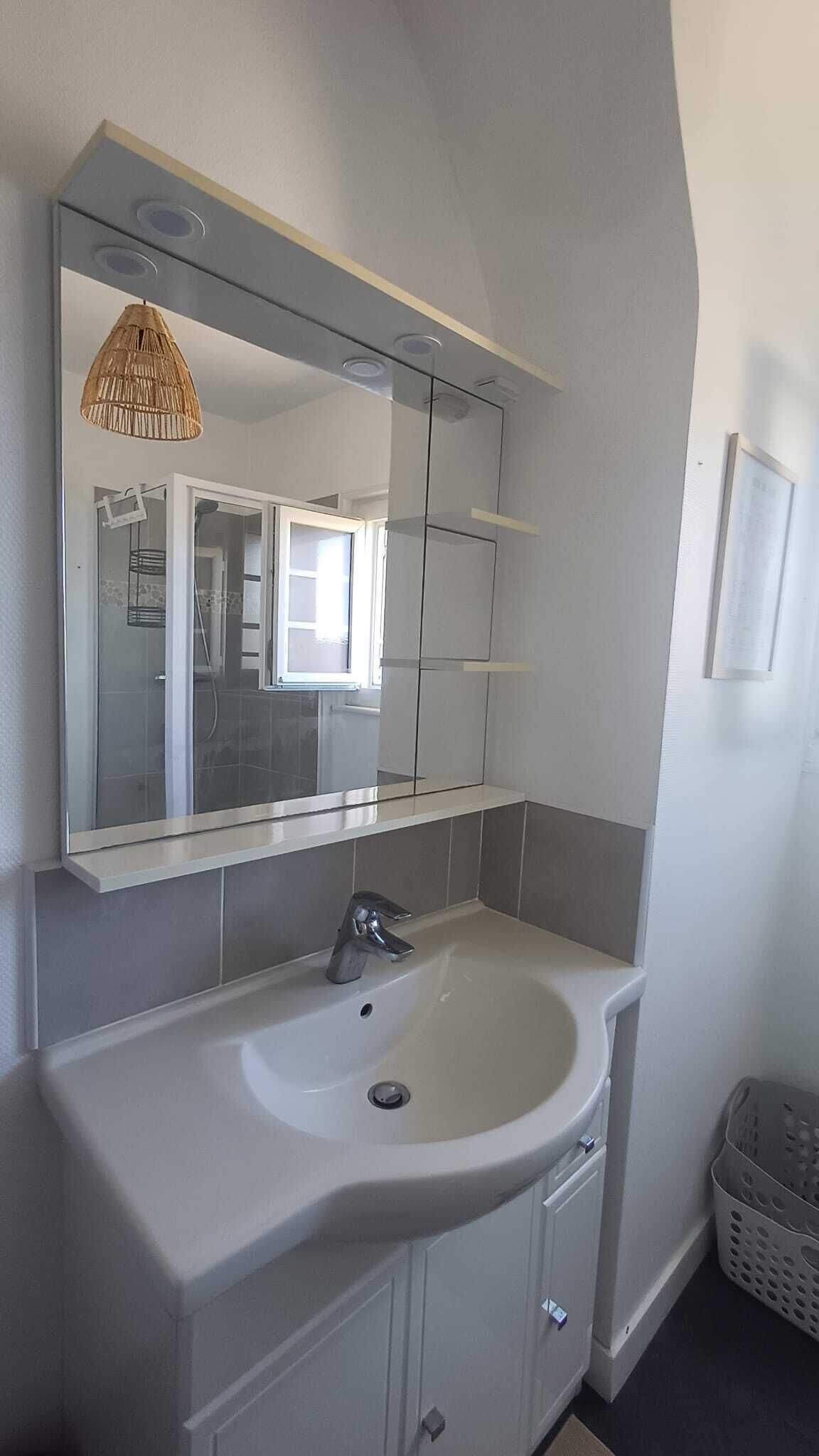 A bathroom with a white sink, a mirror, and a shower enclosure.