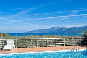 Ein Schwimmbecken mit Blick auf das Meer und die Berge.