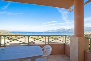 A balcony with a table and chairs, overlooking a coastal landscape with mountains and the sea. - Holiday apartment with 1 bedroom (Saint-Florent)