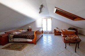 Ein Schlafzimmer mit einem hölzernen Bett, einer Couch, einem kleinen Tisch und einem Fenster mit Vorhängen.