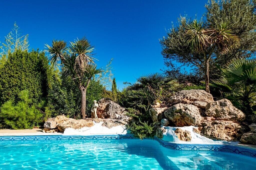 A clear blue pool surrounded by rocks and various trees.