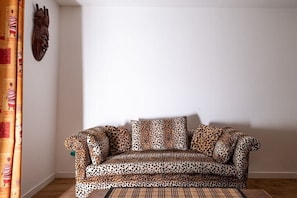 Ein Sofa mit Leopardendruck, ein Holzboden und ein Vorhang mit Muster.
