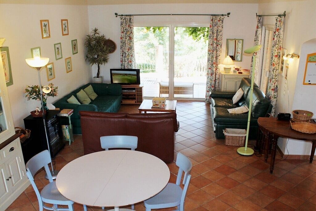Un salon comprenant un canapé, un téléviseur, une table à manger avec des chaises et une porte-fenêtre coulissante donnant sur un espace extérieur.
