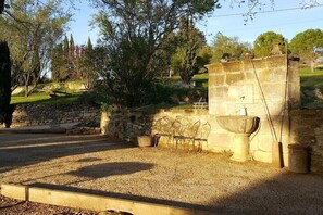 A stone wall with a fountain, outdoor seating, and a gravel area. - Holiday apartment in Apt with swimming pool (Apt)