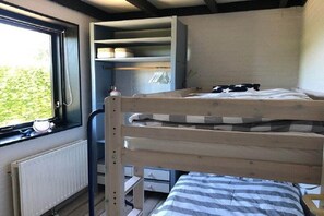 A bunk bed with a window, a radiator, and a shelf with storage items. - Holiday home with 2 bedrooms (Retranchement)