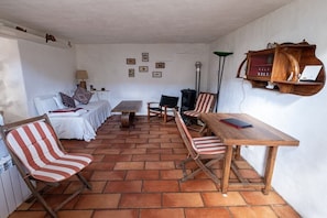 Ein Zimmer mit einem weißen Sofa, gestreiften Stühlen, einem Holztisch und einem an der Wand befestigten Regal.