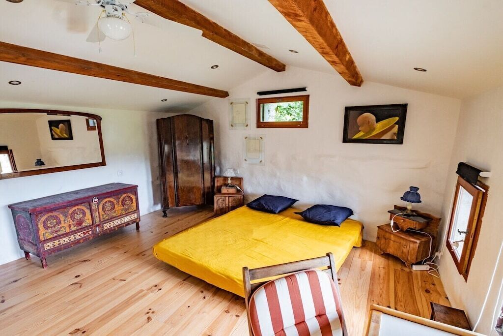 Une chambre à coucher avec un lit, une armoire en bois, une chaise et un miroir.