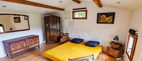 Une chambre à coucher avec un lit, une armoire en bois, une chaise et un miroir.