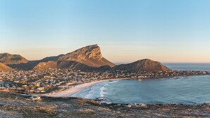 Une ville côtière dominée par une montagne imposante, avec une plage et une vue sur l’océan.