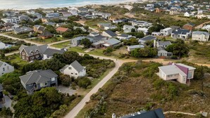 Une zone résidentielle côtière avec des maisons, une plage et une montagne en arrière-plan.