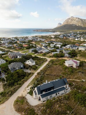Una zona residencial costera con casas, una playa y una montaña al fondo.
