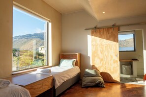 Un dormitorio con cama, un banco de madera, vistas al exterior y un pequeño baño.