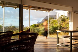 Un interior moderno con ventanas amplias, mobiliario de mimbre y vistas a un paisaje natural.