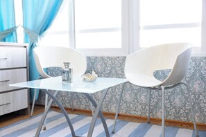 Een kamer met een kleine tafel en twee stoelen, een decoratieve fles en een wand met bloemenmotief.