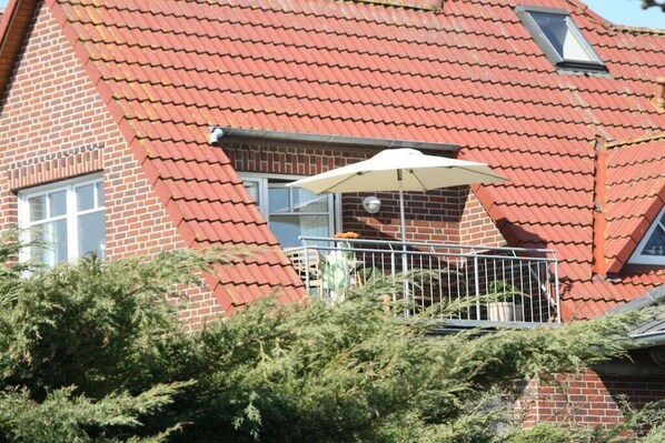 Ein Haus mit roten Ziegeln, einem Balkon, einem Fenster und einem Blumentopf.
