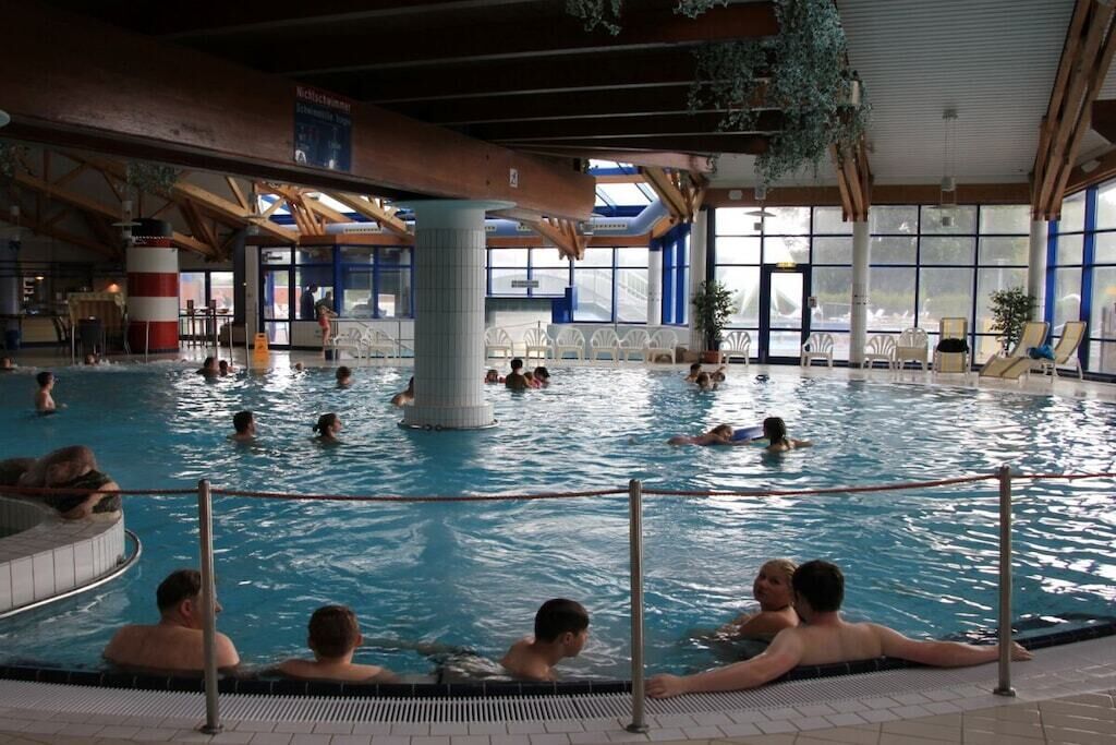 En inomhuspool med flera banor, en central pelare och utsikt mot omgivningen genom stora fönster.