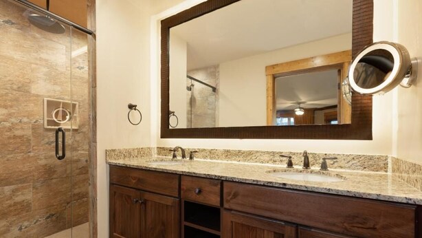 A bathroom with a glass shower enclosure, a double sink vanity, and a large mirror. - Spend Christmas week in a beautiful Smoky Mountain resort with onsite waterpark! (Gatlinburg)