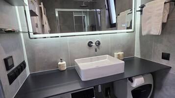 Ein modernes Badezimmer mit Waschmaschine, Waschbecken und Spiegel.