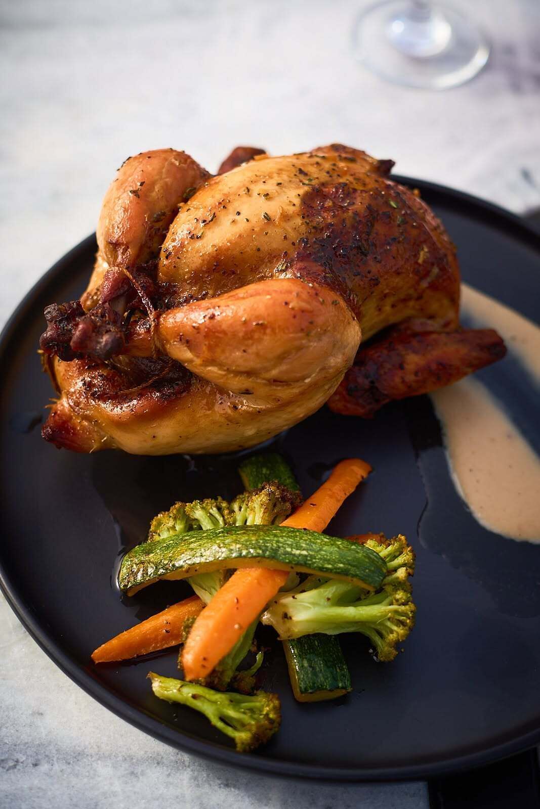 Frango assado com legumes num prato.