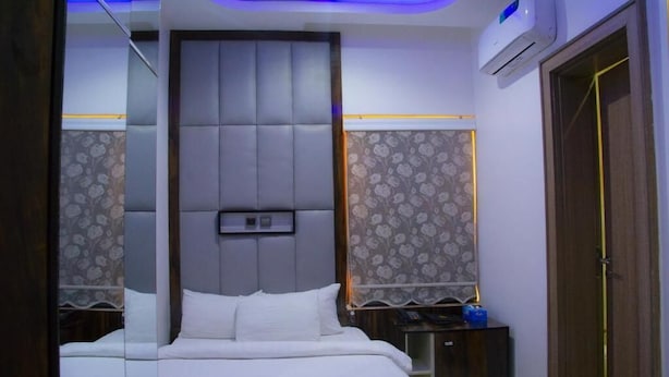 Un dormitorio moderno con una cama grande, cabecera, mesita de noche, equipo de aire acondicionado y armario.