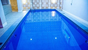Una piscina con suelo de azulejos azules y una pared de celosía blanca decorativa.