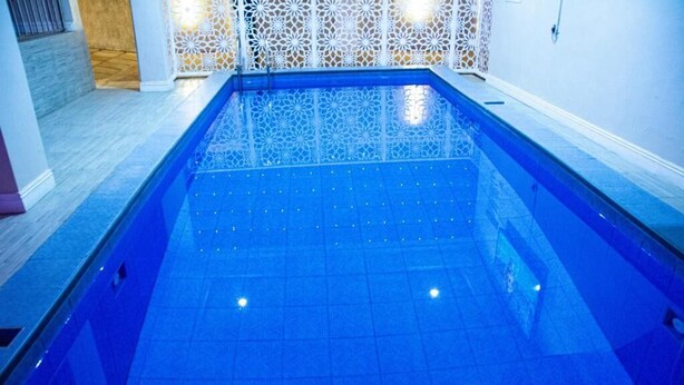 Ein Swimmingpool mit blau gefliestem Boden und einer weißen Zierverkleidung.