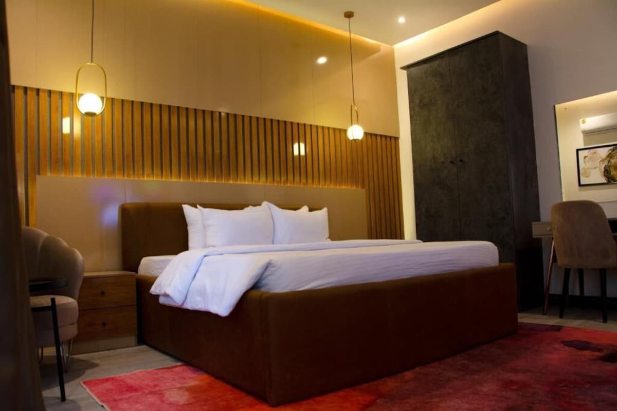 A modern bedroom with a large bed, bedside tables, a chair, and a desk.