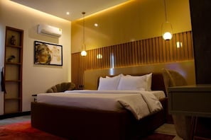 A modern bedroom with a large bed, a wooden headboard, and a wall-mounted air conditioner. - Aviel Hotel And Suites (Abuja)