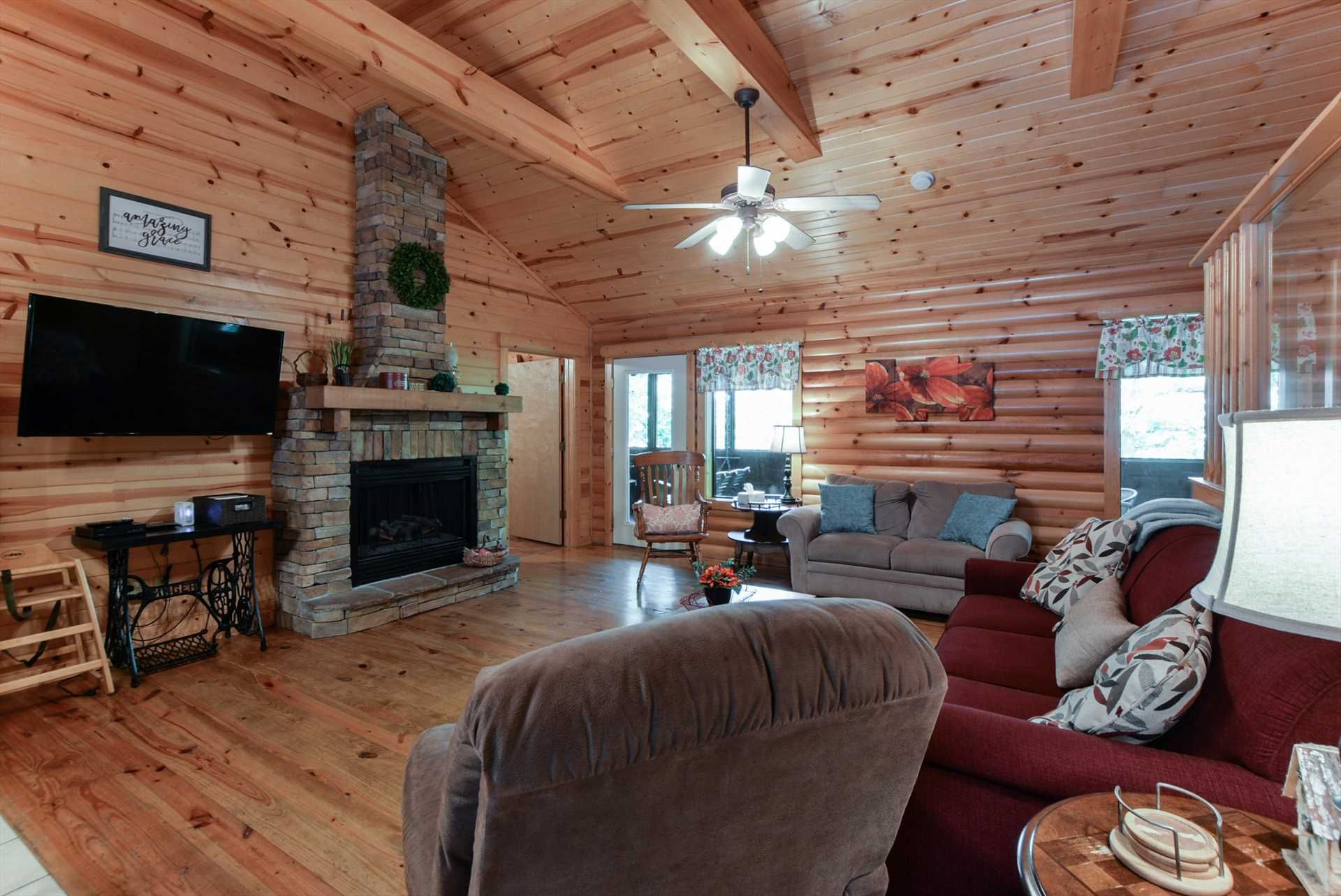 L'intérieur d'une cabane en rondins, avec une cheminée, un téléviseur et un coin salon confortable.